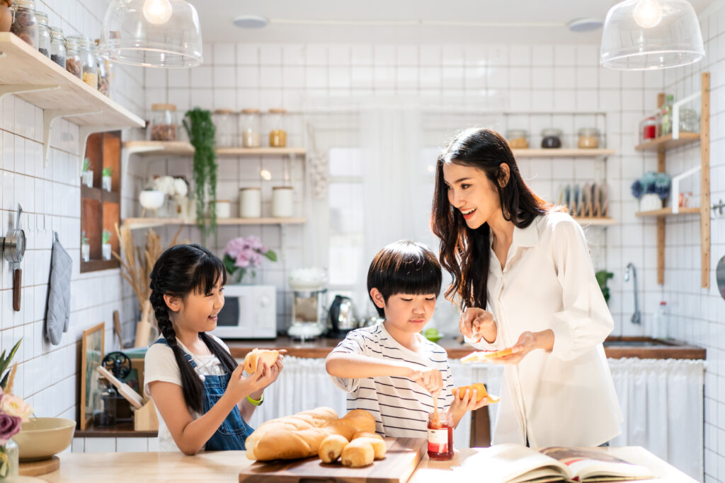 明るいキッチンで子どもたちとパンを楽しむ笑顔の母親
