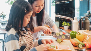 キッチンで母親が子どもに料理を教えている場面