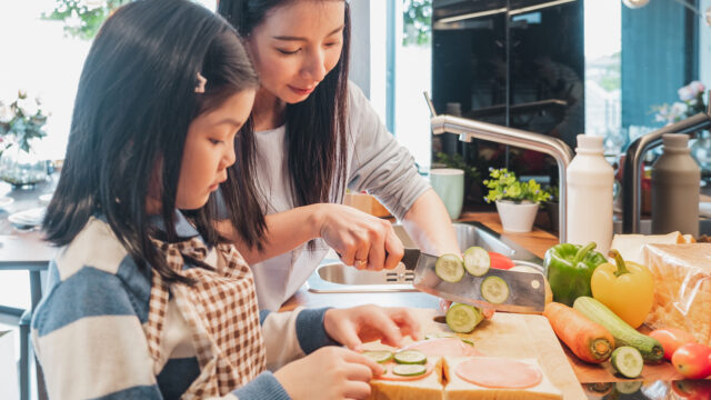 キッチンで母親が子どもに料理を教えている場面