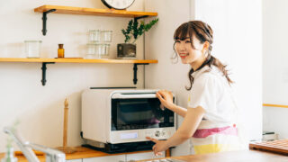 明るいキッチンで調理家電を操作する笑顔の女性