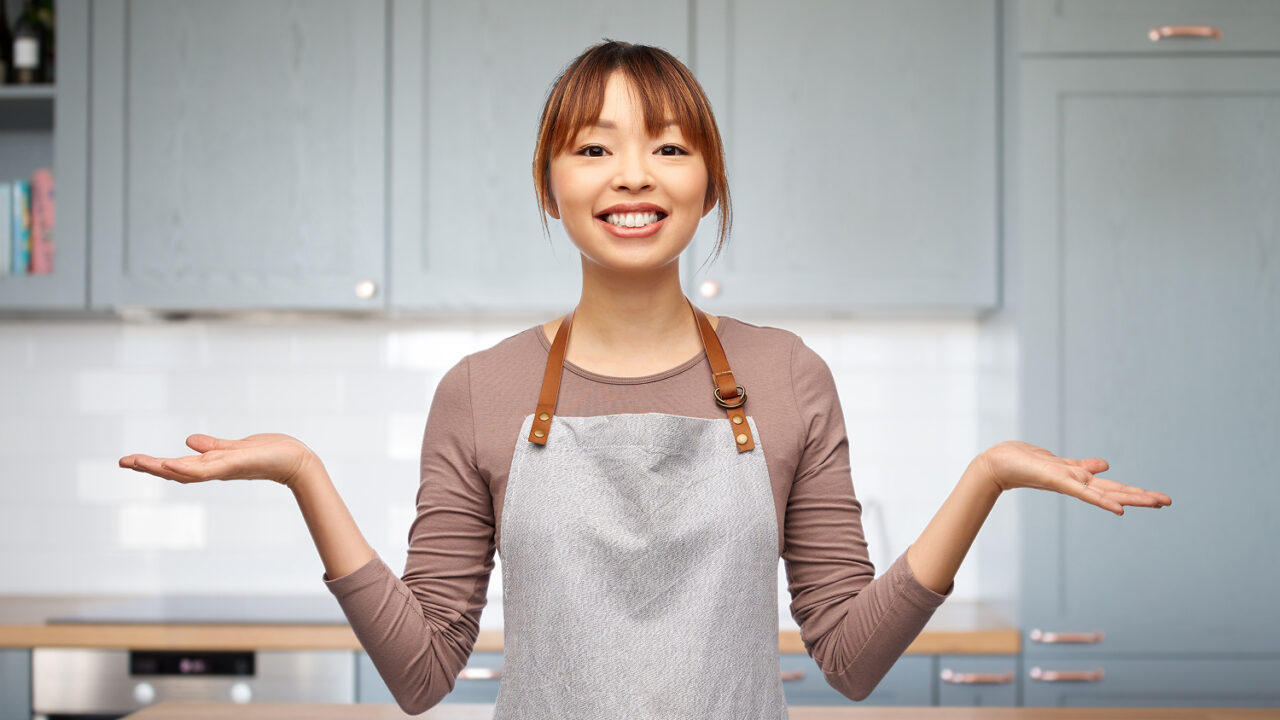 エプロン姿の女性が両手を広げて比較・選択をしているイメージ