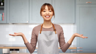 エプロン姿の女性が両手を広げて比較・選択をしているイメージ